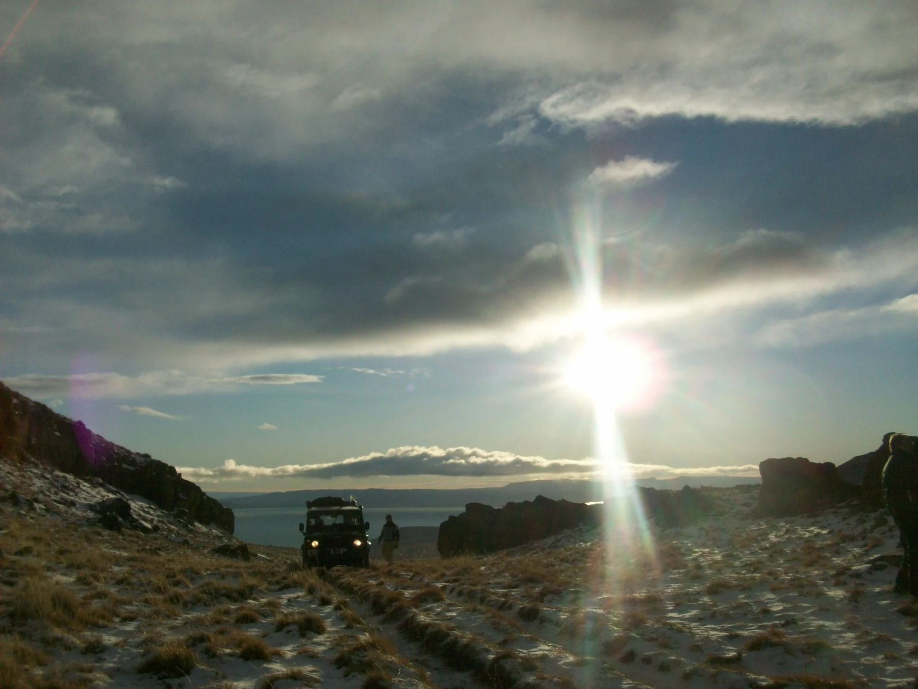 Vehículo en un camino patagónico bajo un cielo nublado