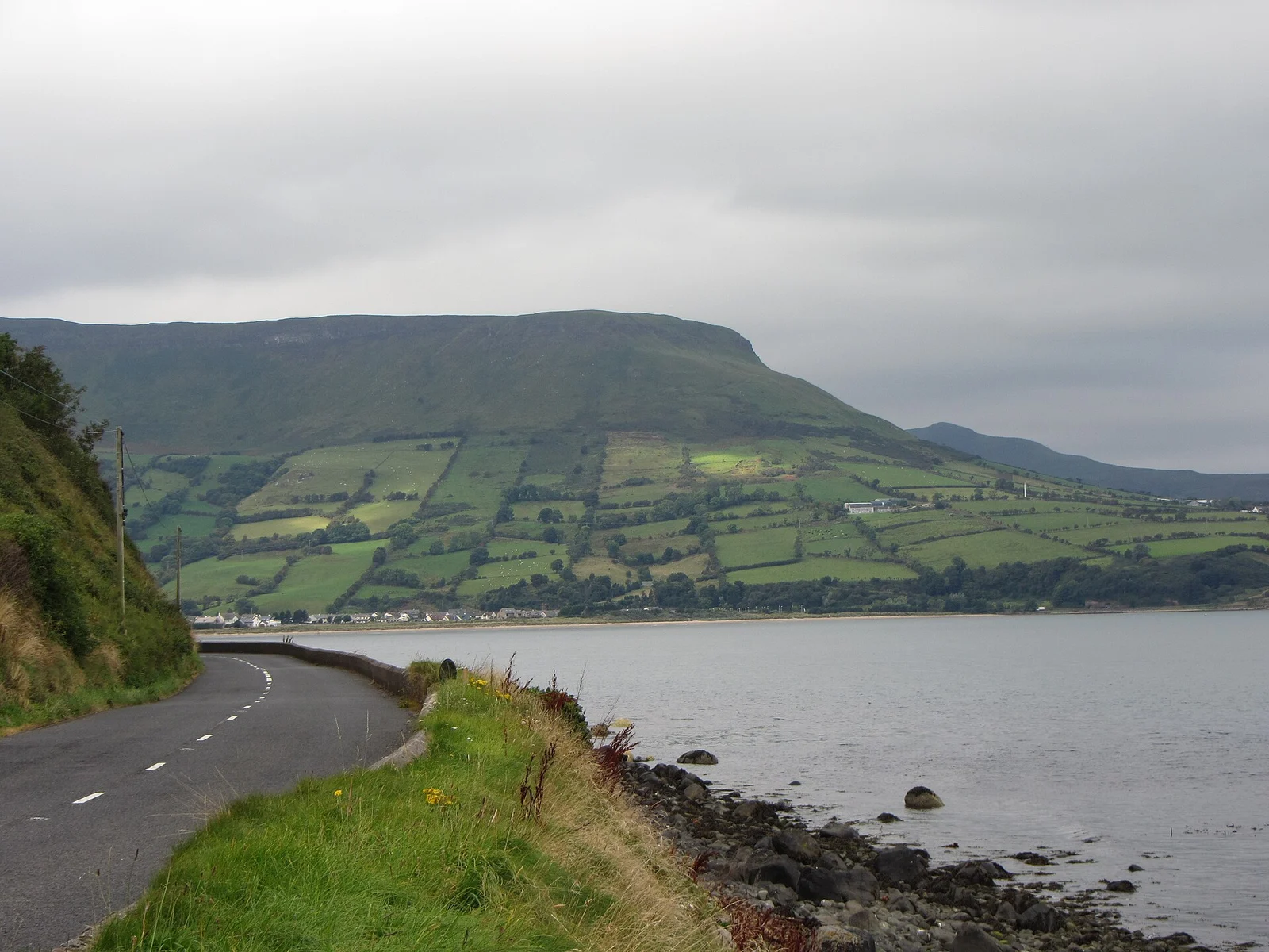 Coastal road beneath green hills near Ardclinis in Northern Ireland